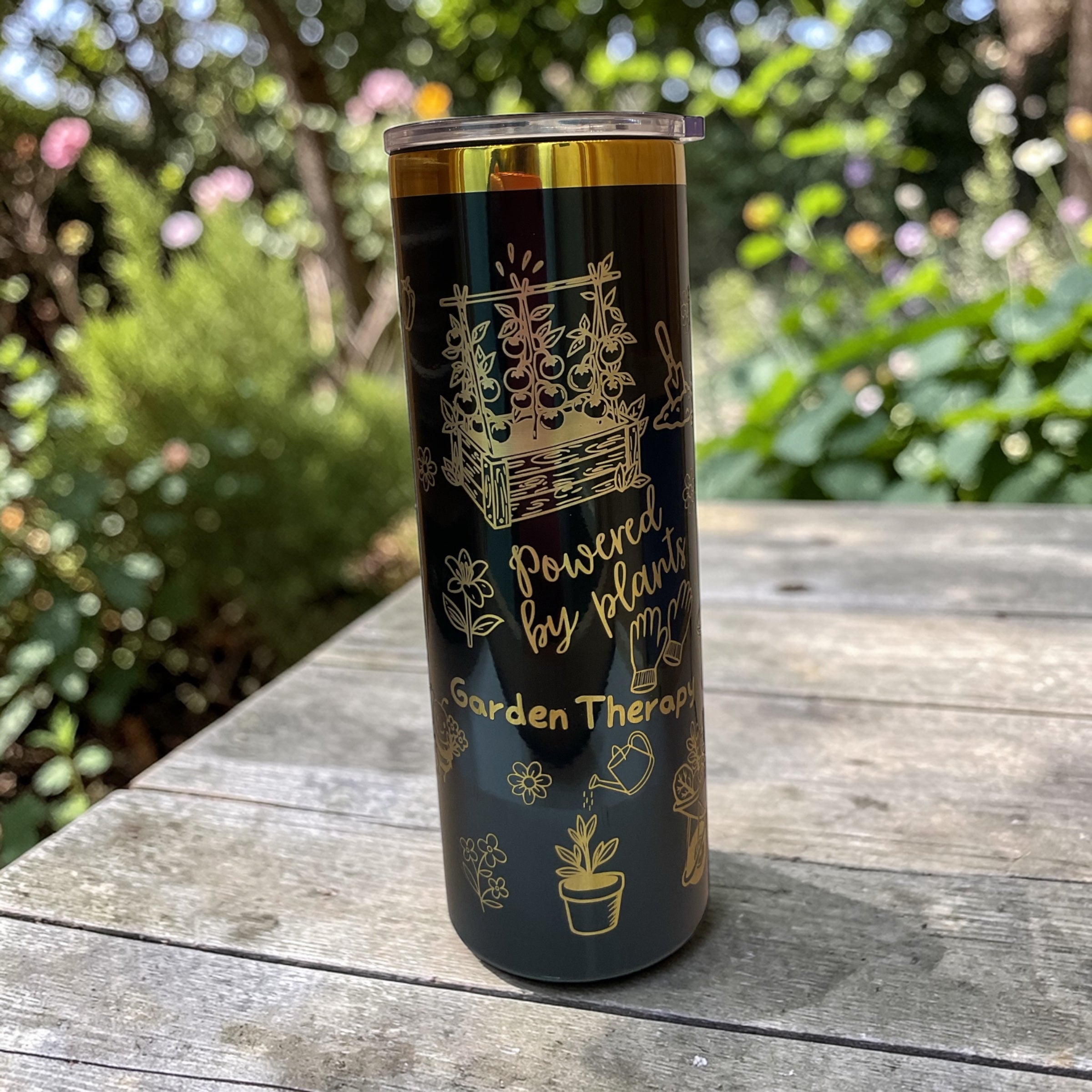Tumbler with garden-themed design on a wooden surface outdoors