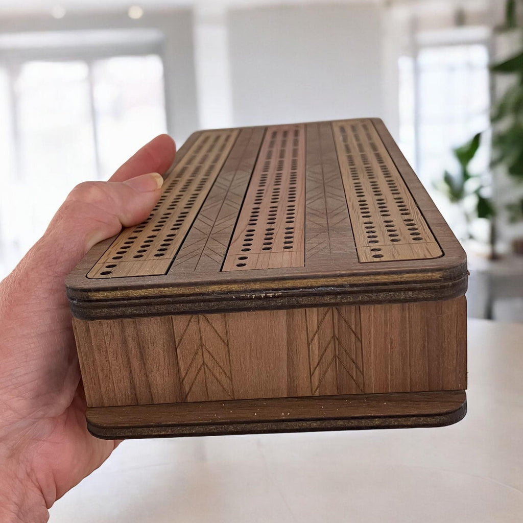 Wooden box with intricate patterns held by a hand in a blurred indoor setting