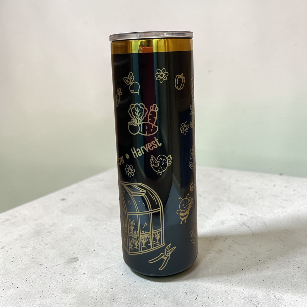 Tumbler with gold illustrations on a white surface