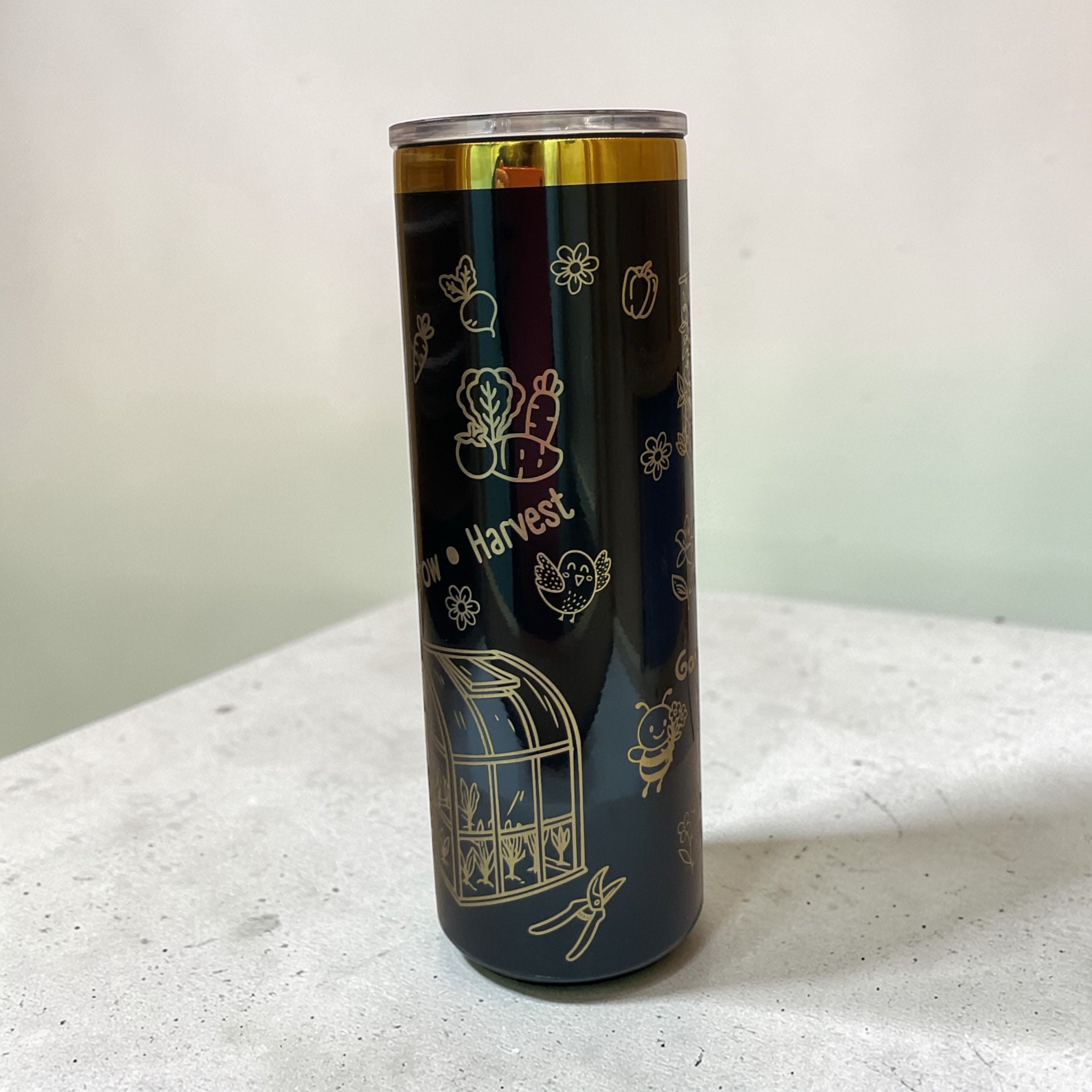 Tumbler with gold illustrations on a white surface