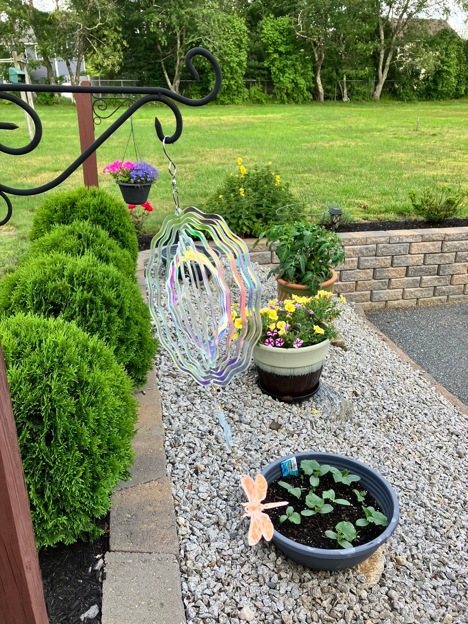 Iridescent flower wind spinner with dragonfly charms hanging in a garden