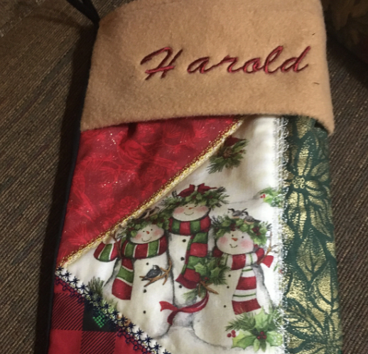 Christmas stocking with 'Harold' embroidered on it, featuring snowmen and holly design.