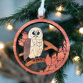 Handcrafted wooden owl Christmas ornament hanging on Christmas tree branch